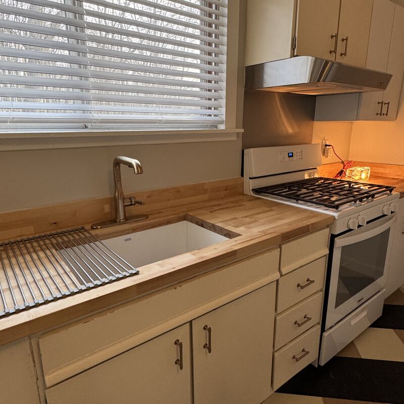 The kitchen sink and gas stove with butcher block counters
